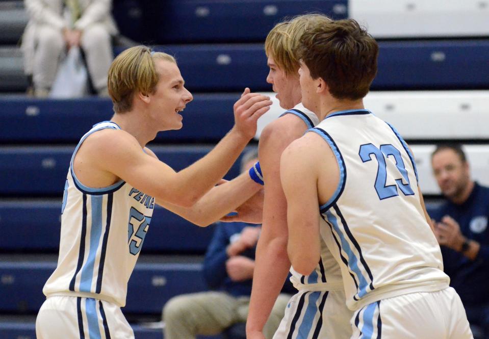 Petoskey's Charlie Smith (left) and Ely Pethers (right) celebrate with teammate Korbin Sulitis after a basket and an and-one opportunity against Elk Rapids Saturday.