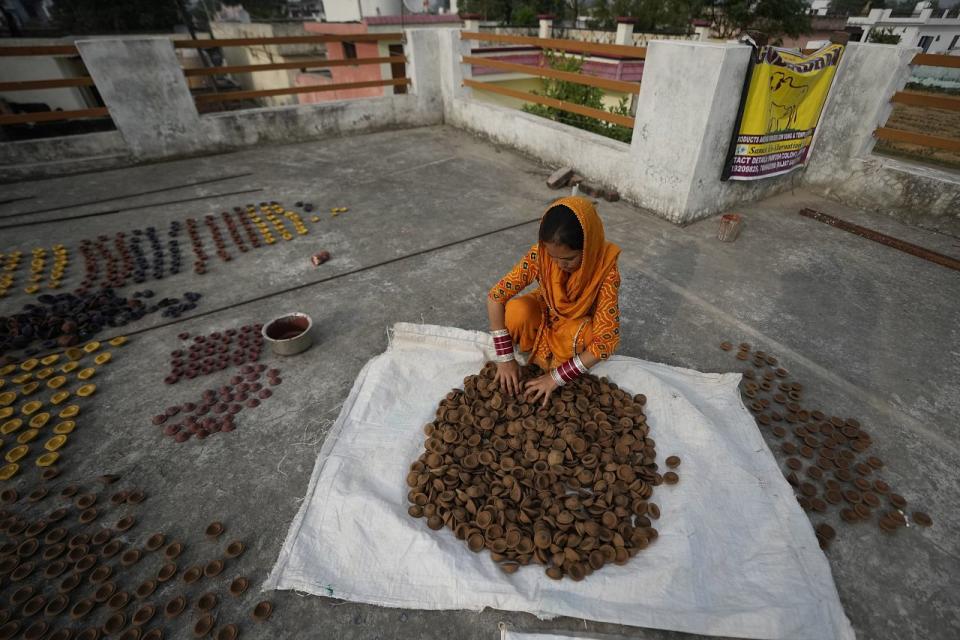 A woman prepares lamps made from cow dung ahead of Diwali in Jammu, India, Tuesday, Nov. 7, 2023.