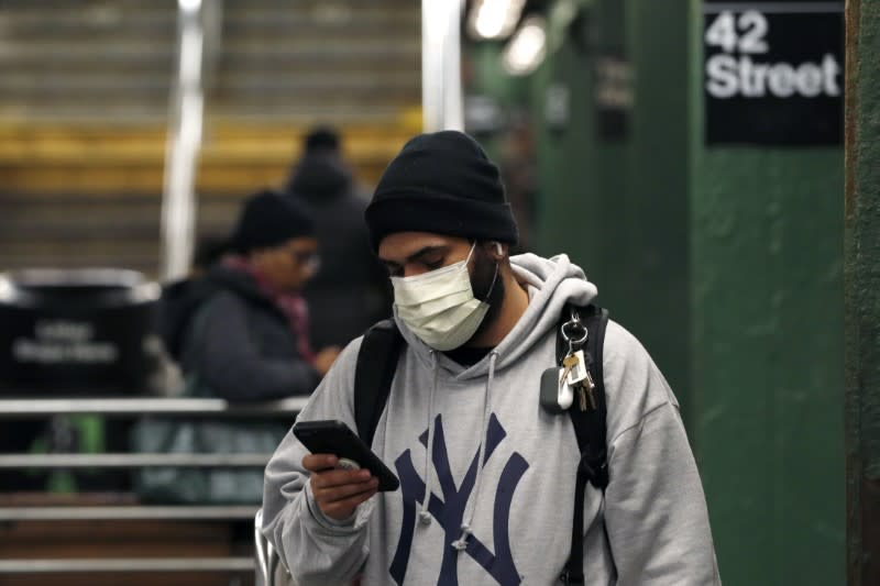 A man wearing a face mask uses his phone in the Times Square subway station, as people react to coronavirus disease (COVID-19) in New York