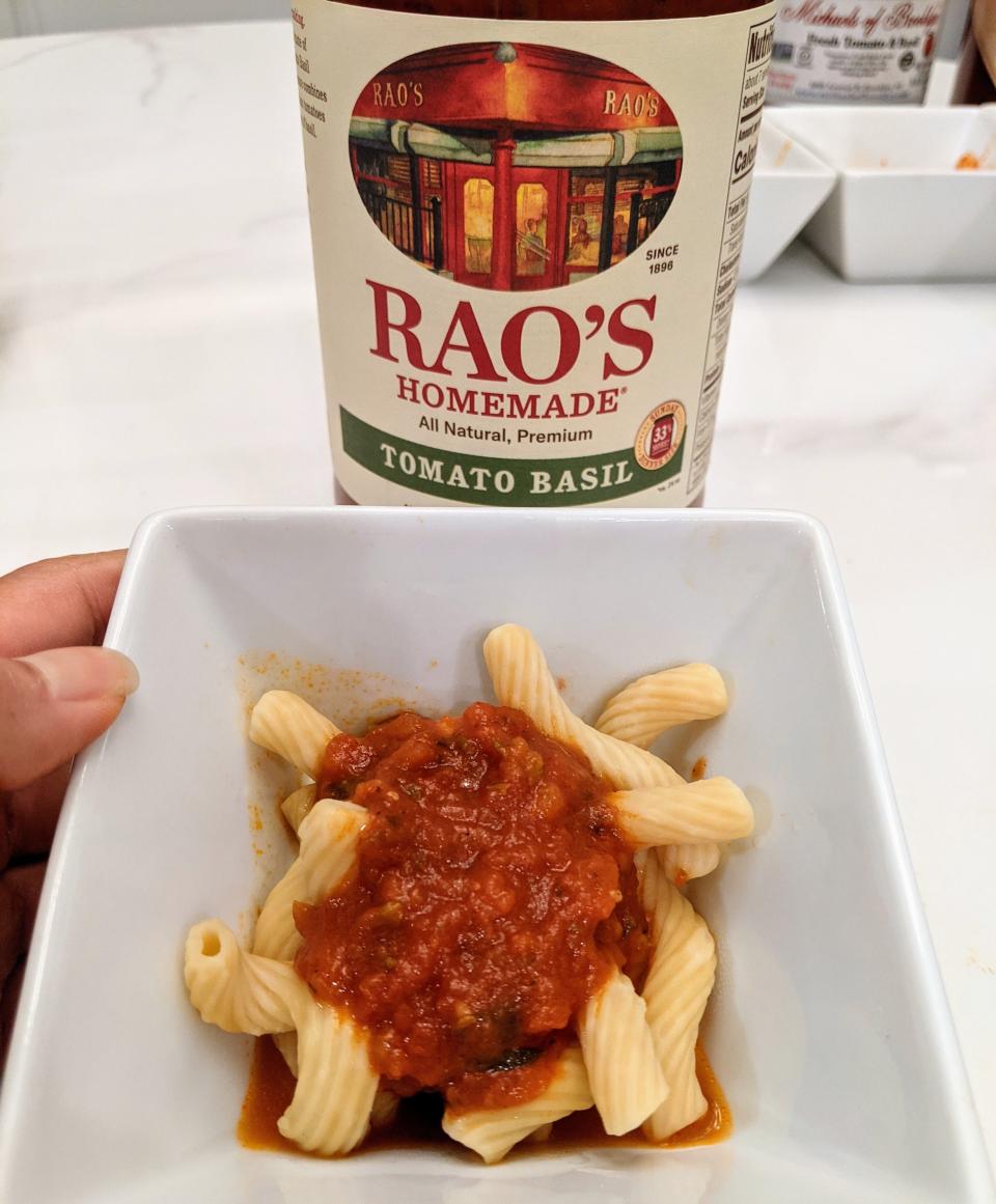 jar of rao's red sauce behind a small white bowl of pasta