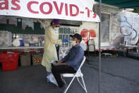 Nurse Tanya Markos administers a coronavirus test on patient Ricardo Sojuel at a mobile COVID-19 testing unit, Thursday, July 2, 2020, in Lawrence, Mass. (AP Photo/Elise Amendola)