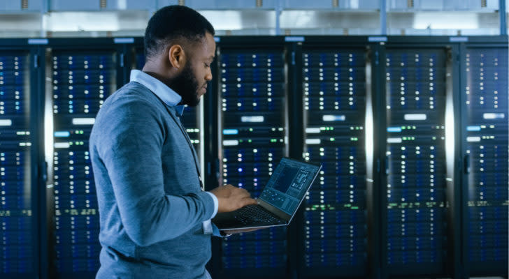 Man in a server room holding a laptop