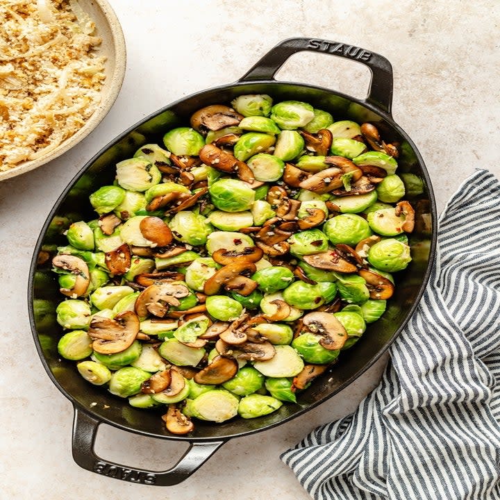 mushrooms and brussels sprouts in an oval-shaped baking dish before being baked