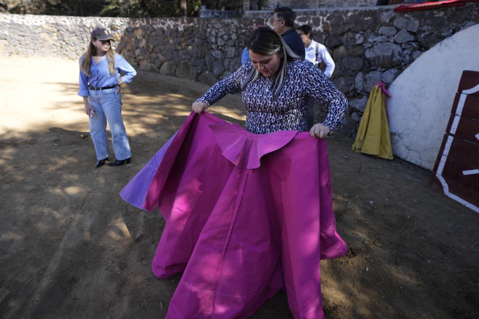 Environmental engineering student Estefania Manrique looks at a capote during a bullfighting workshop, in Aculco, Mexico, Thursday, Jan. 25, 2024. Manrique says that at first she hesitated to accompany her mother to a bullfight because she “had this idea that it was abuse,” but her perception changed when she began to understand the ritual that surrounded the show. (AP Photo/Fernando Llano)