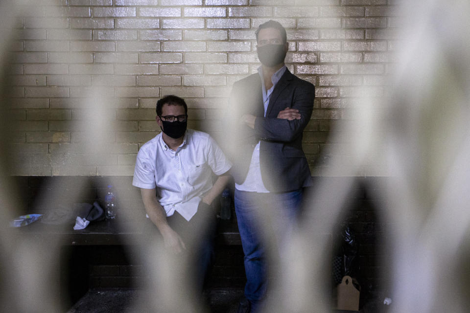 The sons of former Panamanian President Ricardo Martinelli, Ricardo Martinelli Linares, right, and his brother Luis Enrique wait inside a cell at the judicial court building in Guatemala City, Tuesday, July 7, 2020. The brothers were detained Monday on an international warrant from Interpol on charges of conspiracy to commit money laundering. (AP Photo/Moises Castillo)