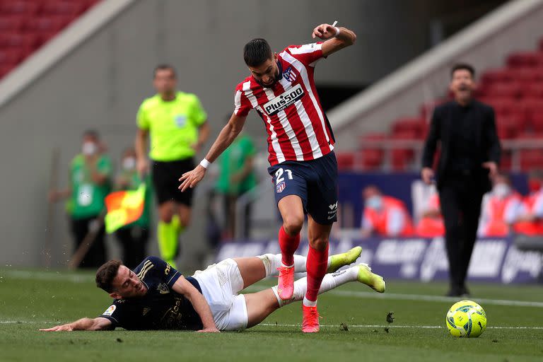 Yannick Carrasco lucha por la pelota con Enrique Barja durante un partido entre el Atlético Madrid y el Osasuna.