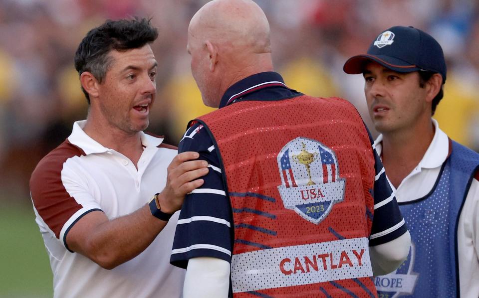 Rory McIlroy speaks with Joe LaCava, the caddie of Patrick Cantlay, on the 18th green