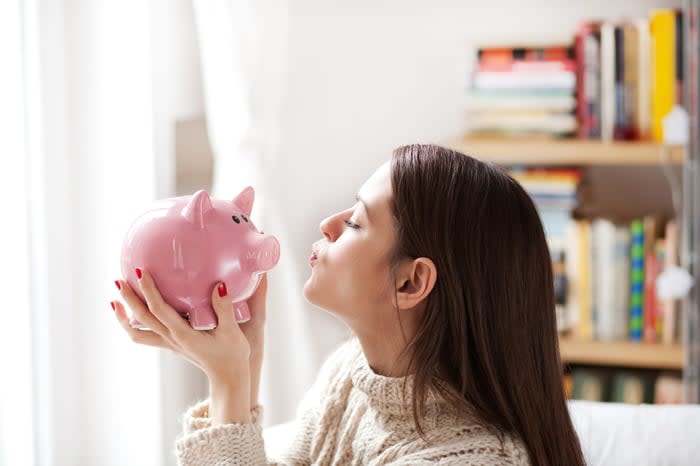 A person kissing a piggy bank.