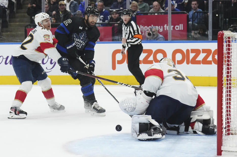 Florida Panthers goaltender Alex Lyon (34) stops a shot from Toronto Maple Leafs forward Zach Aston-Reese (12) as Panthers defenseman Gustav Forsling (42) defends during the second period of an NHL hockey game in Toronto on Wednesday, March 29, 2023. (Nathan Denette/The Canadian Press via AP)