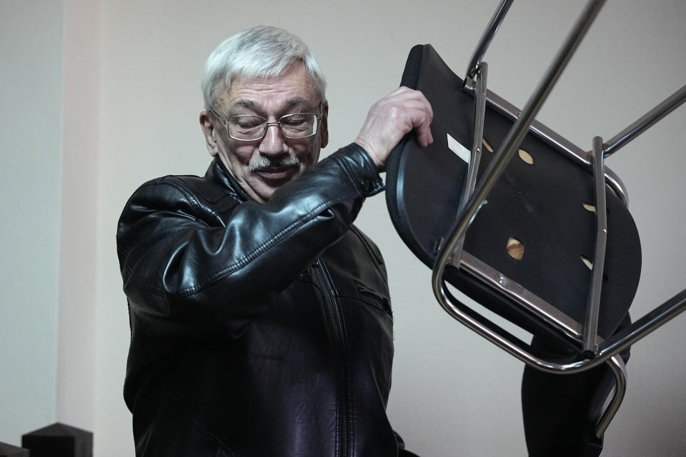 Oleg Orlov, a member of the Board of the International Historical Educational Charitable and Human Rights Society 'Memorial' (International Memorial) carries a chair at a courtroom prior to a session in Moscow, Russia, Wednesday, Oct. 11, 2023. Orlov, the co-chair of the Nobel Peace Prize-winning human rights group Memorial, is on trial on charges of 