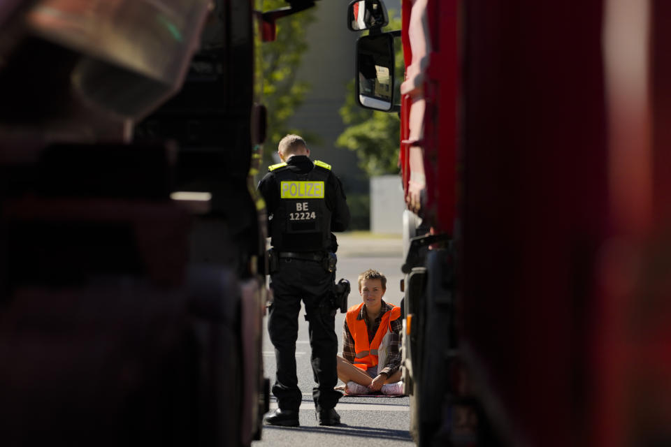 A police officer talks to a climate activist during a protest with the group Uprising of the Last Generation in Berlin, Germany, Tuesday, June 21, 2022. The group claims the world has only a few years left to turn the wheel around and avoid catastrophic levels of global warming. (AP Photo/Markus Schreiber)