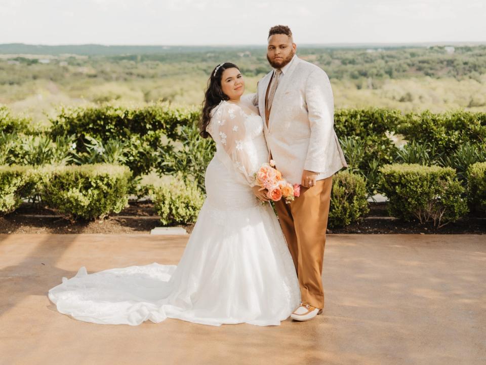 A bride and groom hold hands under a veranda.