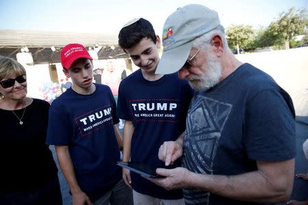 Israeli American Sruly Cooper (R) signs to vote in the US elections in front of members of the U.S. Republican party's election campaign team in Israel during a campaign aimed at potential American voters living in Israel, near a mall in Modi'in, Israel August 15, 2016. REUTERS/Baz Ratner