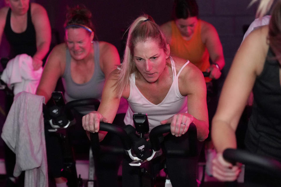 Deb Figulski participates in a spin class at Fuel Training Studio, Thursday, Jan. 19, 2023, in Newburyport, Mass. Gyms and fitness studios were among the hardest hit businesses during the pandemic. But for gyms who made it through the worst, signs of stability are afoot. (AP Photo/Mary Schwalm)