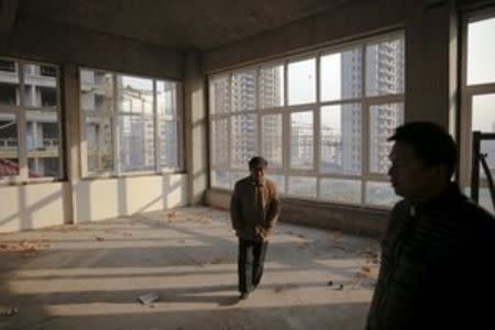 Migrant workers walk inside an unfinished building at the construction site of Zixia Garden development complex in Qianan, Tangshan City, Hebei province, China January 28, 2016. REUTERS/Damir Sagolj