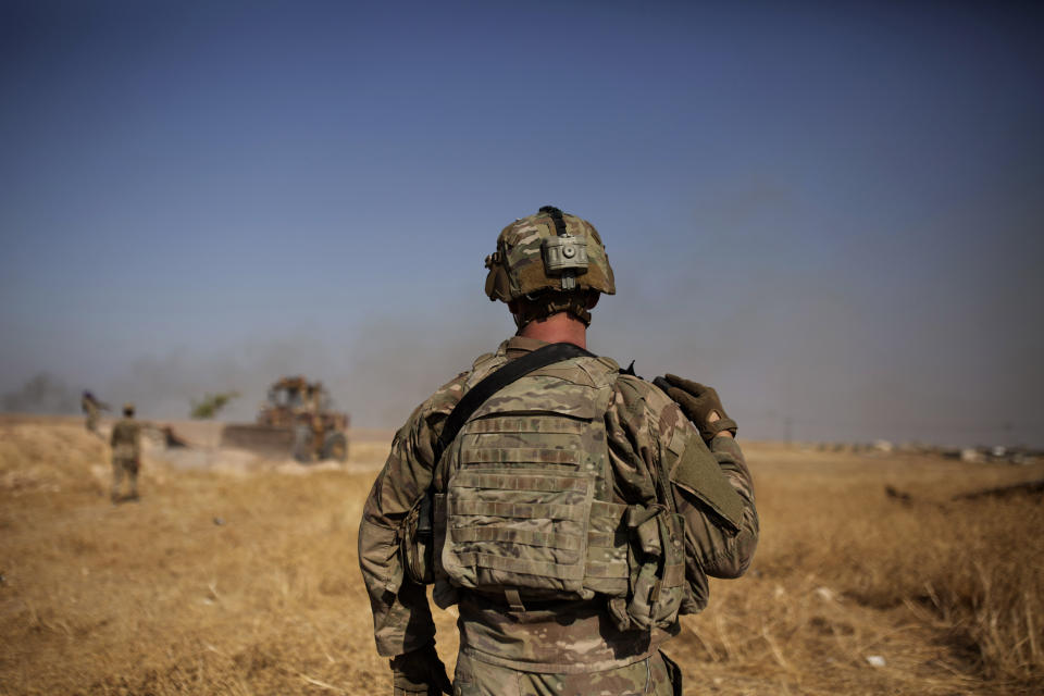 A U.S. special forces soldier watches Syrian Kurdish soldiers dismantle a fortification in the so-called 