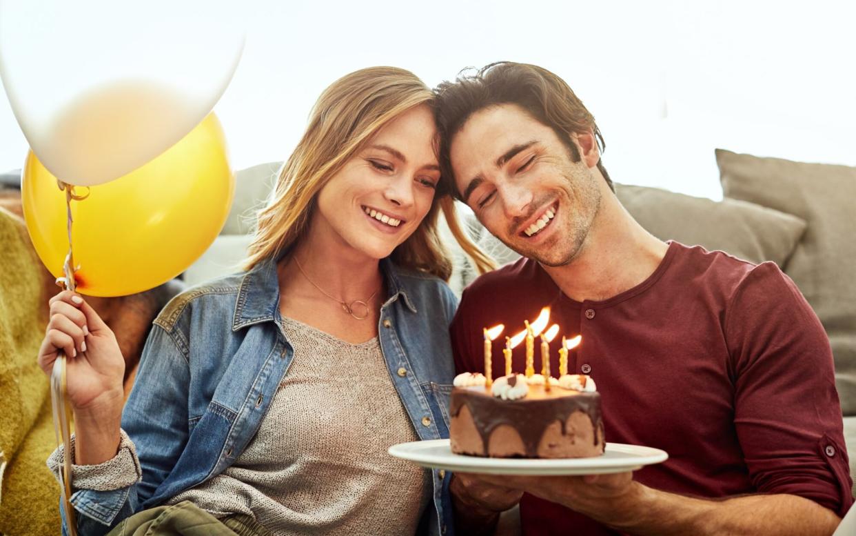Young Couple Sharing Birthday Cake with Balloons