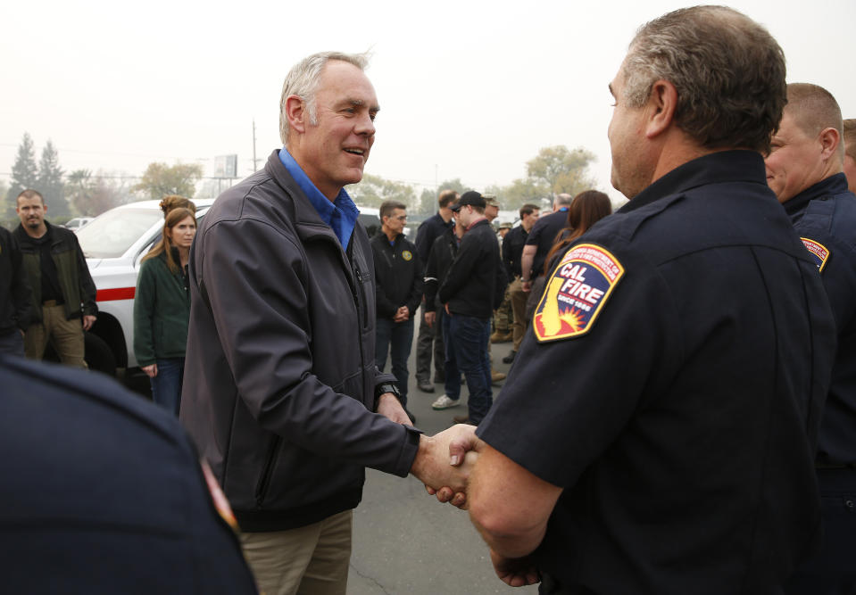 File - In this Nov. 14, 2018 file photo, U.S. Secretary of the Interior Ryan Zinke , left, talks with Matthew Watkins of the California Department of Forestry and Fire Protection after touring the fire ravaged town of Paradise, Calif. The Federal Emergency Management Agency says it has distributed more than $20 million in assistance for people displaced by Northern California's catastrophic wildfire. FEMA spokesman Frank Mansell told The Associated Press that $15.5 million has been spent on housing assistance and $5 million on other needs like funeral expenses. Zinke and US Agriculture Secretary Sonny Perdue were scheduled to visit the community of Paradise, which was incinerated by the fire that ignited in the parches Sierra Nevada foothills Nov. 8 and quickly spread across 240 square miles (620 square kilometers).(AP Photo/Rich Pedroncelli, File)