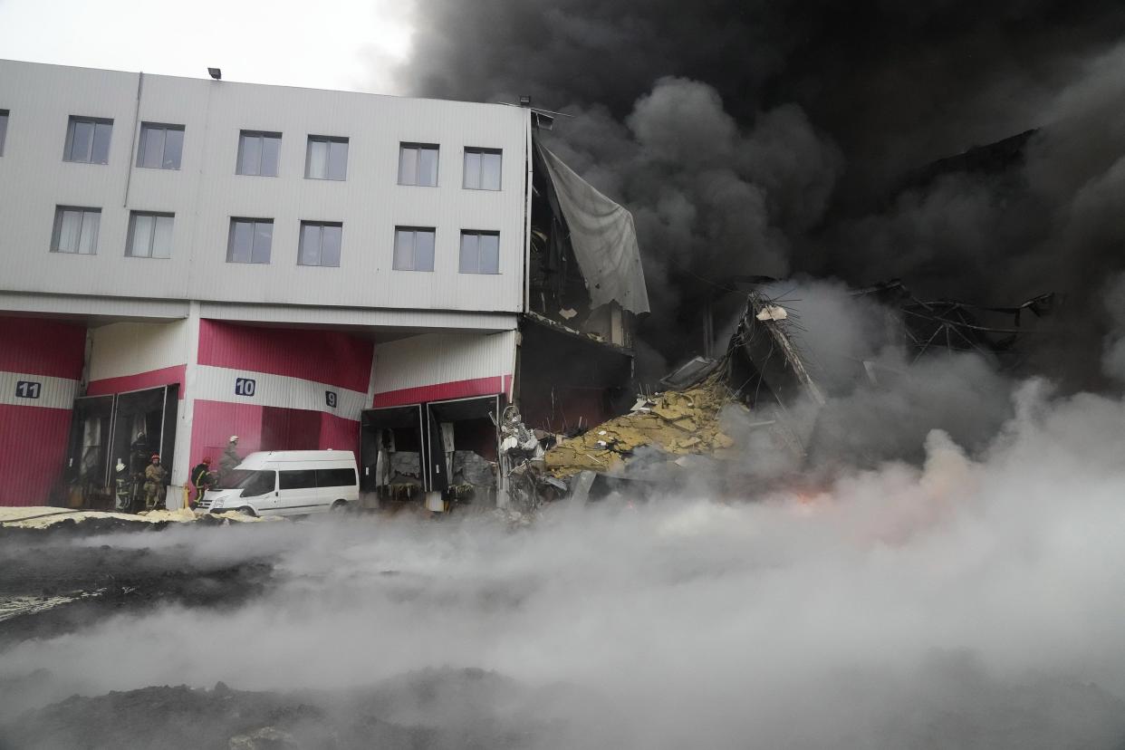 Firefighters work to extinguish a fire at a damaged logistic center after shelling in Kyiv, Ukraine, Thursday, March 3, 2022.