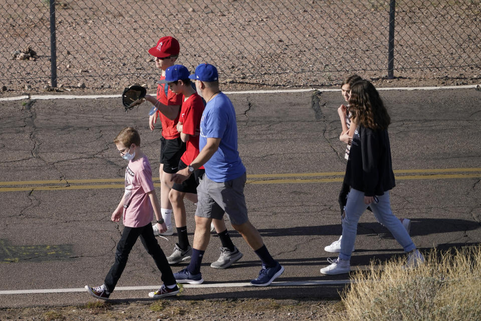 Fans walk along a service road in an effort to see Los Angeles Angels players during a spring training baseball practice, Tuesday, Feb. 23, 2021, in Tempe, Ariz. (AP Photo/Matt York)