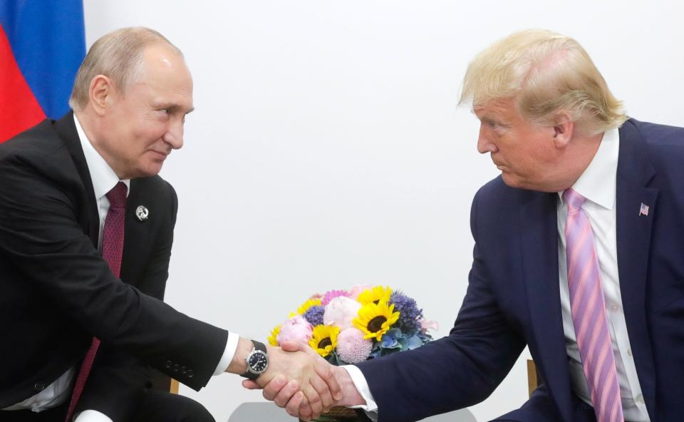 Russian President Vladimir Putin and then-President Donald Trump shake hands.