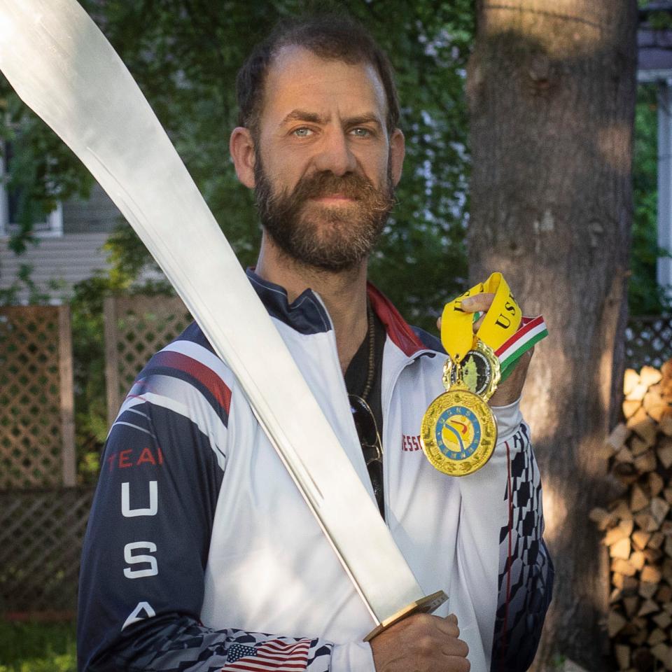 Jesse Shadoan, a Poughkeepsie resident and Tai Chi instructor, poses with his sword and a gold medal he won last year at the U.S. Kuo Shu martial arts tournament.