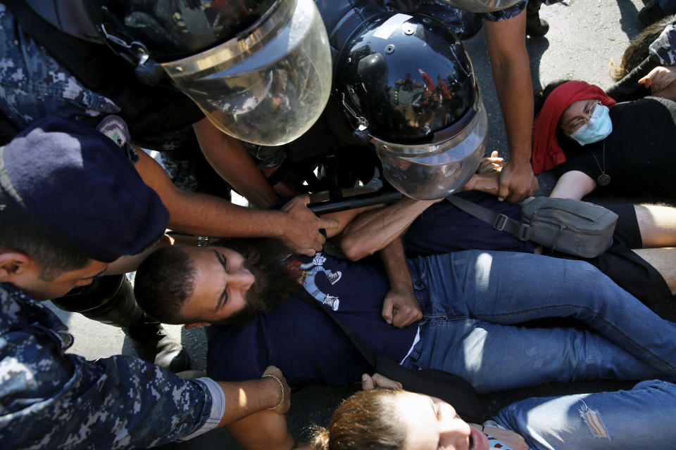 Anti-government protesters lie on a road and hold each others as riot police try to remove them and open the road, in Beirut, Lebanon, Thursday, Oct. 31, 2019. Army units and riot police took down barriers and tents set up in the middle of highways and major intersections Thursday. (AP Photo/Bilal Hussein)