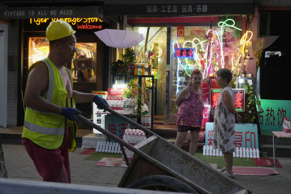 A worker pushes a cart past stores in Beijing, Tuesday, Aug. 15, 2023. Chinese leader Xi Jinping has called for patience in a speech released as the ruling Communist Party tries to reverse a deepening economic slump and said Western countries are "increasingly in trouble" because of their materialism and "spiritual poverty." (AP Photo/Ng Han Guan)
