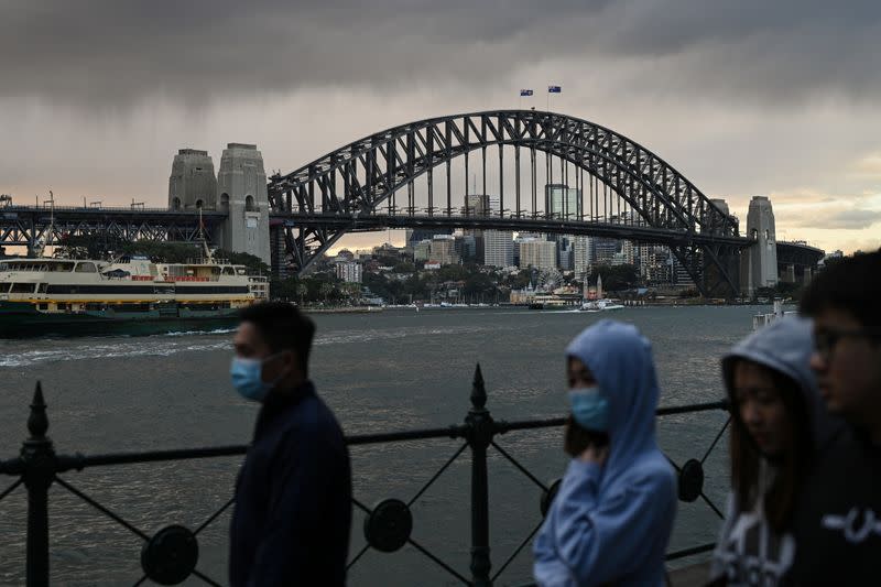 People walk in front of the Sydney Harbour Bridge in Sydney