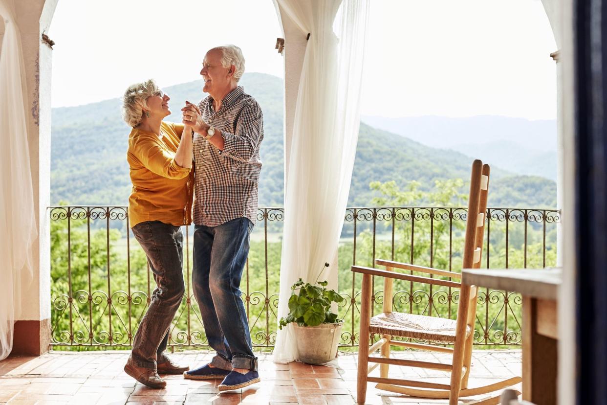 senior couple dancing on balcony in mountainous region