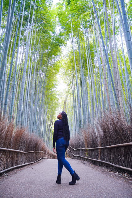 woman standing in walkway of tall forest