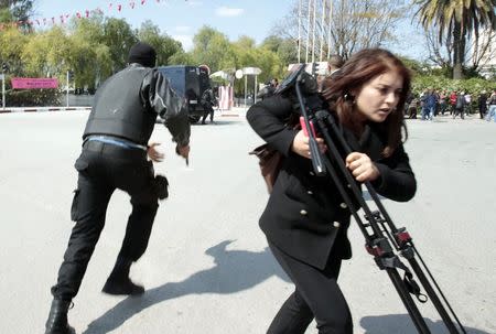 Police officers and a journalist run outside the parliament in Tunis March 18, 2015. REUTERS/ Zoubeir Souissi