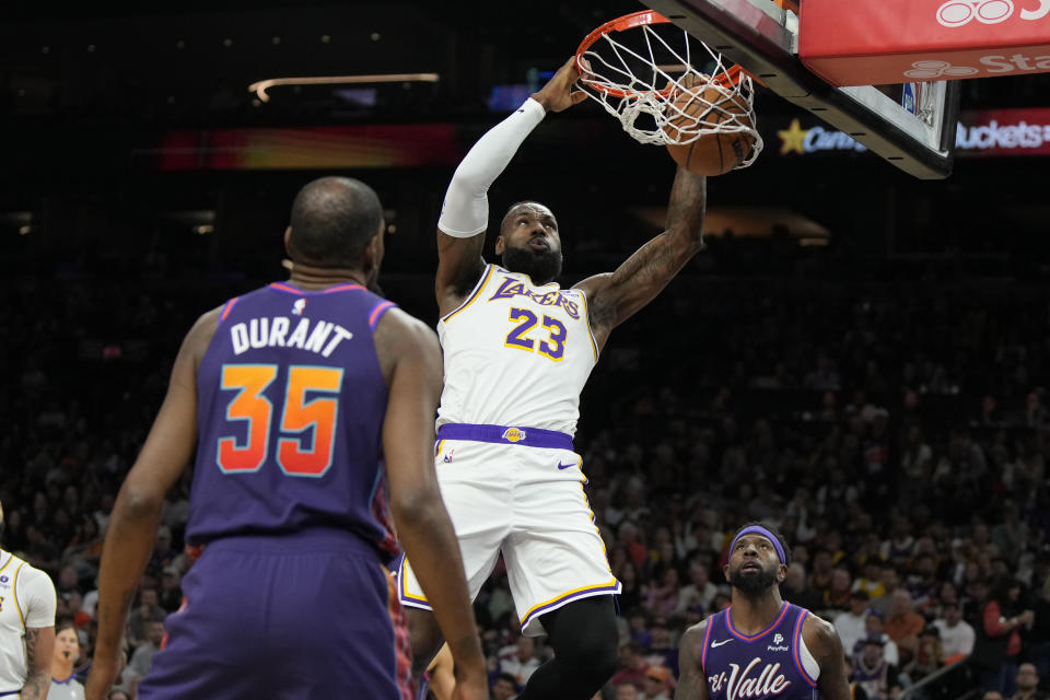 Los Angeles Lakers forward LeBron James (23) dunks over Phoenix Suns forward Kevin Durant (35) and forward Royce O'Neale during the first half of an NBA basketball game, Sunday, Feb. 25, 2024, in Phoenix. (AP Photo/Rick Scuteri)