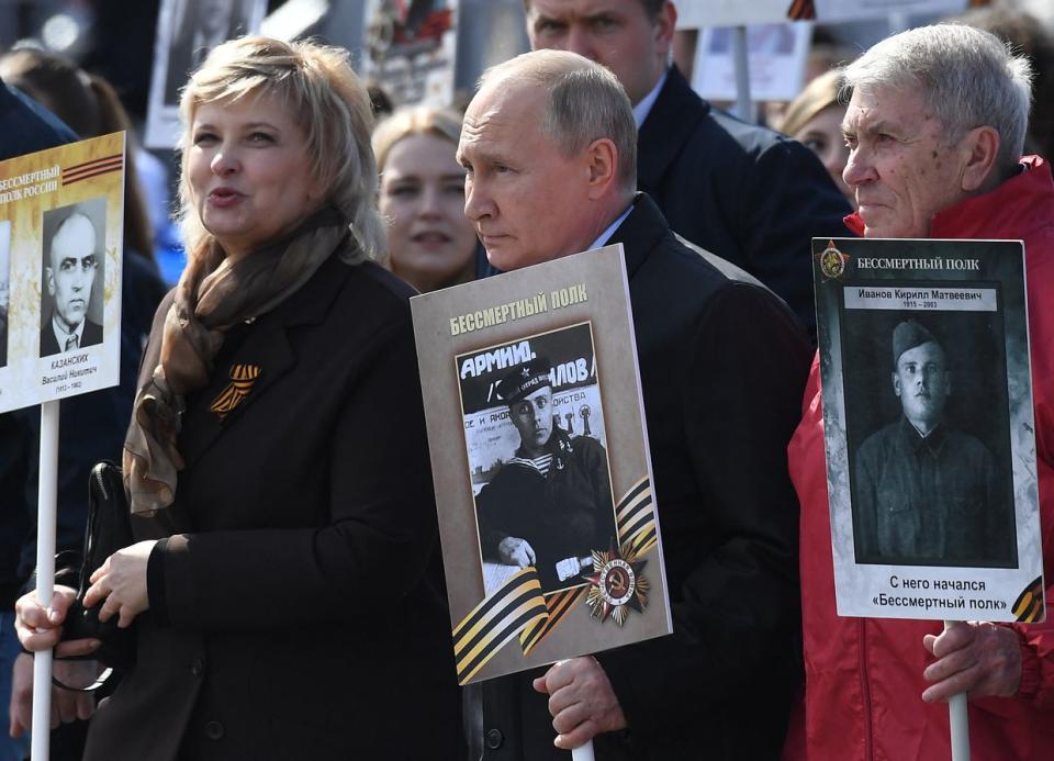Russian President Vladimir Putin and other participants carry portraits of their relatives - World War II soldiers - as they take part in the Immortal Regiment march on Red Square in central Moscow on May 9, 2022. - Russia celebrates the 77th anniversary of the victory over Nazi Germany during World War II. (Natalia Kolesnikova /AFP via Getty Images)