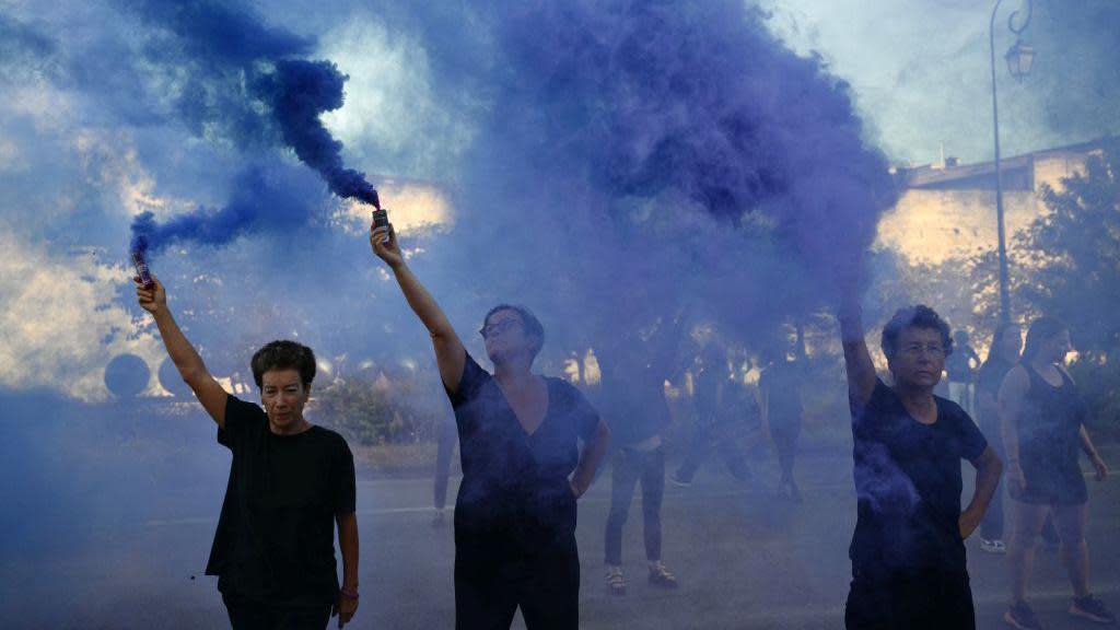 Demonstrators hold smoke bombs during a protest outside the courthouse during the trial of a man accused of drugging his wife Gisèle Pelicot for nearly 10 years and inviting strangers to rape her at their home in Mazan, a small town in the south of France, in Avignon, on September 2, 2024