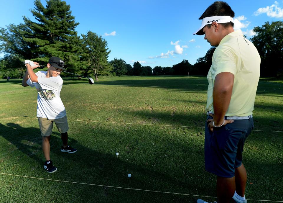 Pro Golfer Carl Yuan originally from China, but now lives in Jacksonville, Florida, right, helps Charles Holloway of Springfield, 14, of the Springfield Golf Club with his golf driving at the Lincoln Greens Golf Course Tuesday July 12. 2022.