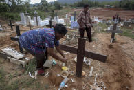 An Indonesian migrant worker places candles on the grave of her husband who worked on a Malaysian palm oil plantation in Sabah, Malaysia, on Sunday, Dec. 9, 2018. As global demand for palm oil surges, plantations are struggling to find enough laborers, frequently relying on brokers who prey on the most at-risk people. The bodies of migrants who die are sometimes not sent home. (AP Photo/Binsar Bakkara)