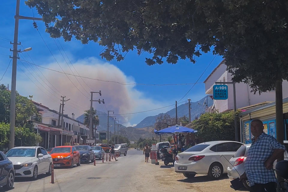 In this image from video, smoke rises from a wild fire in the mountains close to Mesudiye village, Turkey, Wednesday, July 13, 2022. A wildfire, stoked by strong winds, forced authorities on Wednesday to evacuate a number of homes near a resort in southwestern Turkey, officials said. (AP Photo/Oguzhan Arslan)