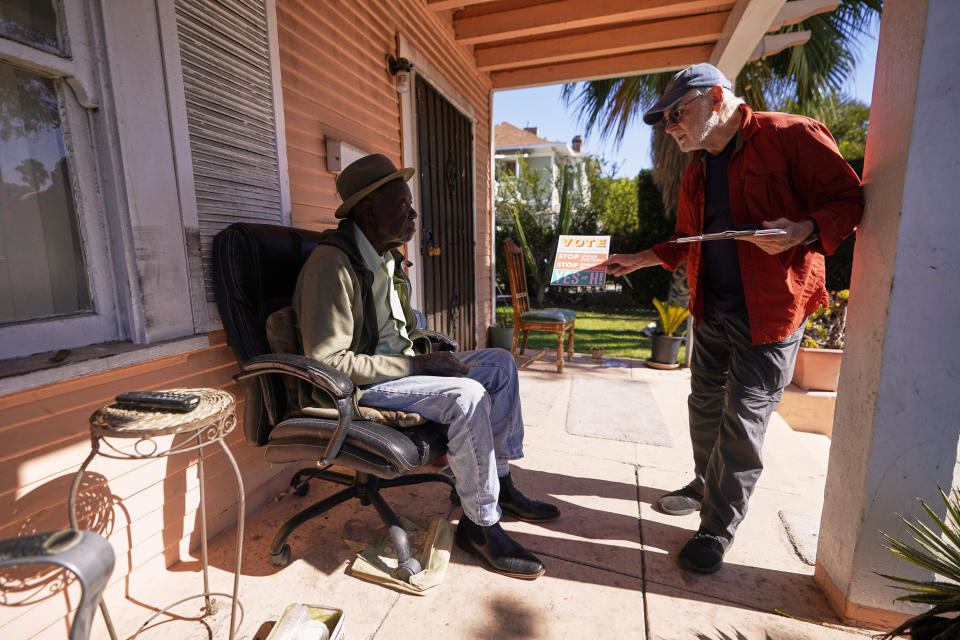 Yes on Measure H! volunteer Ed Washatka talks to home owner Luc Anthony, left, in Pasadena, Calif., Saturday, Oct. 29, 2022. Cities across the country are pushing measures to stabilize or control rents when housing prices are skyrocketing. Voters from Orange County, Florida, and in several California cities are asking voters to approve ballot measures that would cap rent increases. (AP Photo/Damian Dovarganes)
