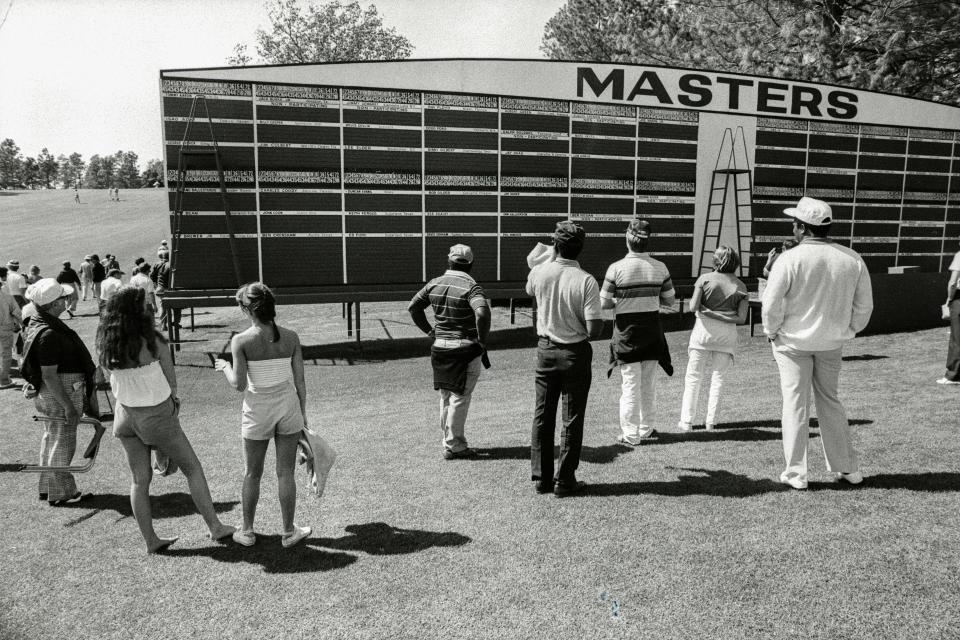 Spectators look at the main scoreboard along the No. 1 fairway blank leader board during the 1981 Masters.