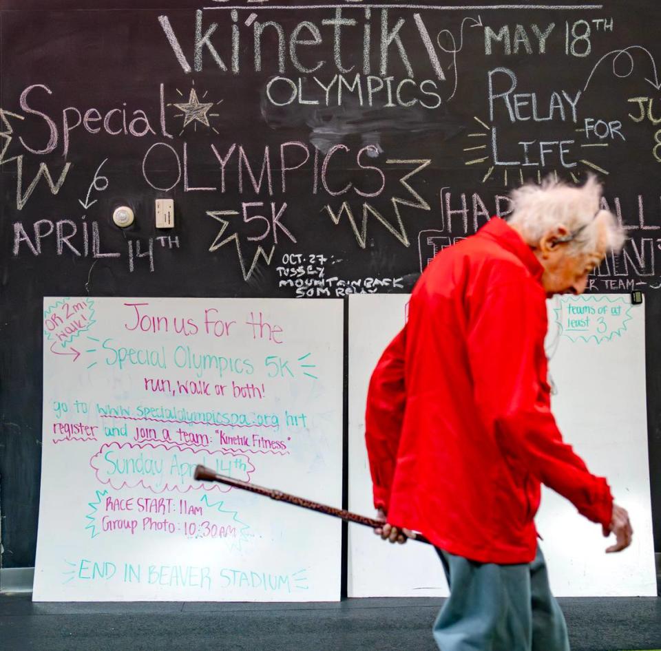 George Etzweiler walks past a sign promoting the Ki’netik Fitness team participating in the Special Olympics run on Friday, April 5, 2024. George, who is 104, is training to do the 2 mile walk.