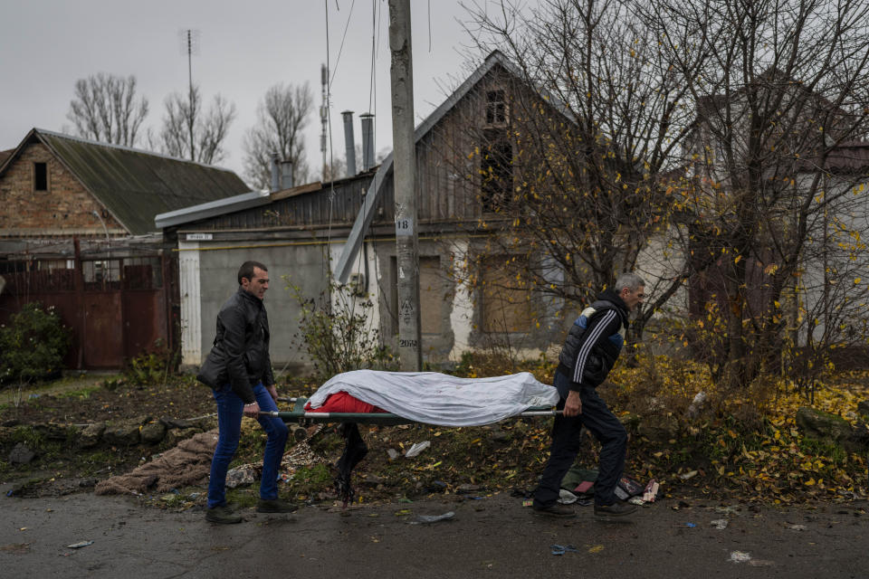 City workers collect the body of a man in Kherson, southern Ukraine, Friday, Nov. 25, 2022. The man died during a Russian attack on Thursday. (AP Photo/Bernat Armangue)