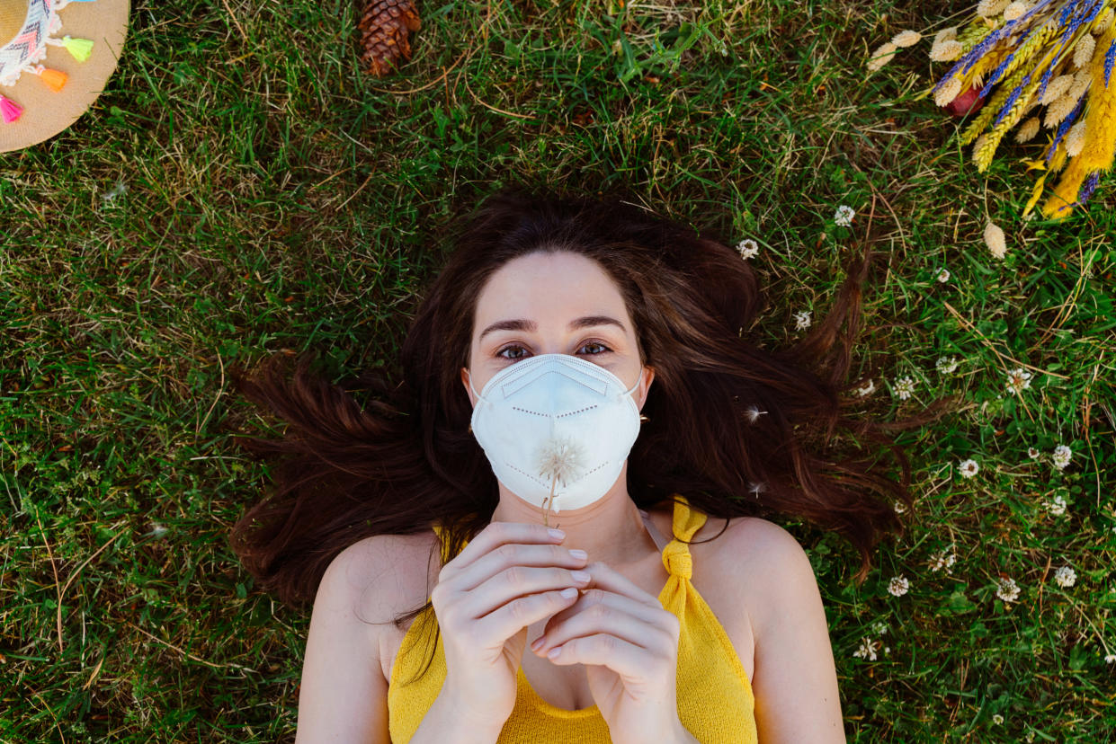 A woman wearing a face mask and lying on the grass.