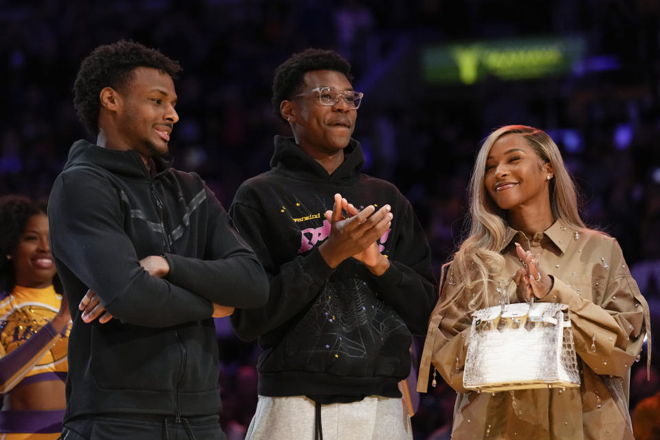 FILE - From left, Bronny James, Bryce James, and Savannah James applaud during a ceremony honoring Los Angeles Lakers forward LeBron James as the NBA's all-time leading scorer before an NBA game against the Milwaukee Bucks on Thursday, Feb. 9, 2023, in Los Angeles. Bronny James was hospitalized after going into cardiac arrest while participating in a practice at Southern California on Monday, July 24, 2023. (AP Photo/Mark J. Terrill, File)