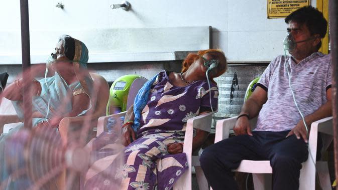 Pasien bernapas dengan bantuan oksigen yang disediakan oleh Gurudwara (Kuil Sikh) di bawah tenda yang dipasang di sepanjang tepi jalan di Ghaziabad, India, Selasa (4/5/2021). Amukan tsunami COVID-19 di India memunculkan kelangkaan oksigen (Money SHARMA/AFP)