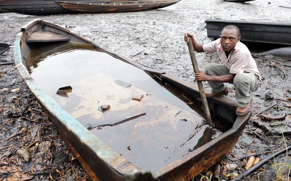 An indigene of Bodo, Ogoniland region in Rivers State, tries to separate with a stick the crude oil from water in a boat at the Bodo waterways polluted by oil spills attributed to Shell equipment failure August 11, 2011 - PIUS UTOMI EKPEI/AFP/Getty Images