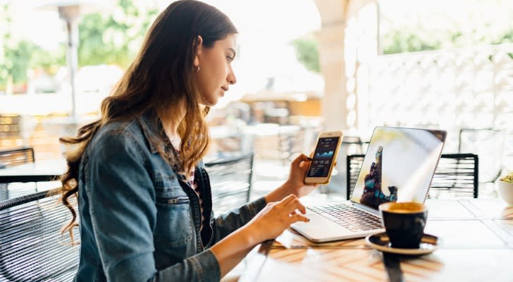 A woman reviews her portfolio and investment strategy while sitting at a cafe. 