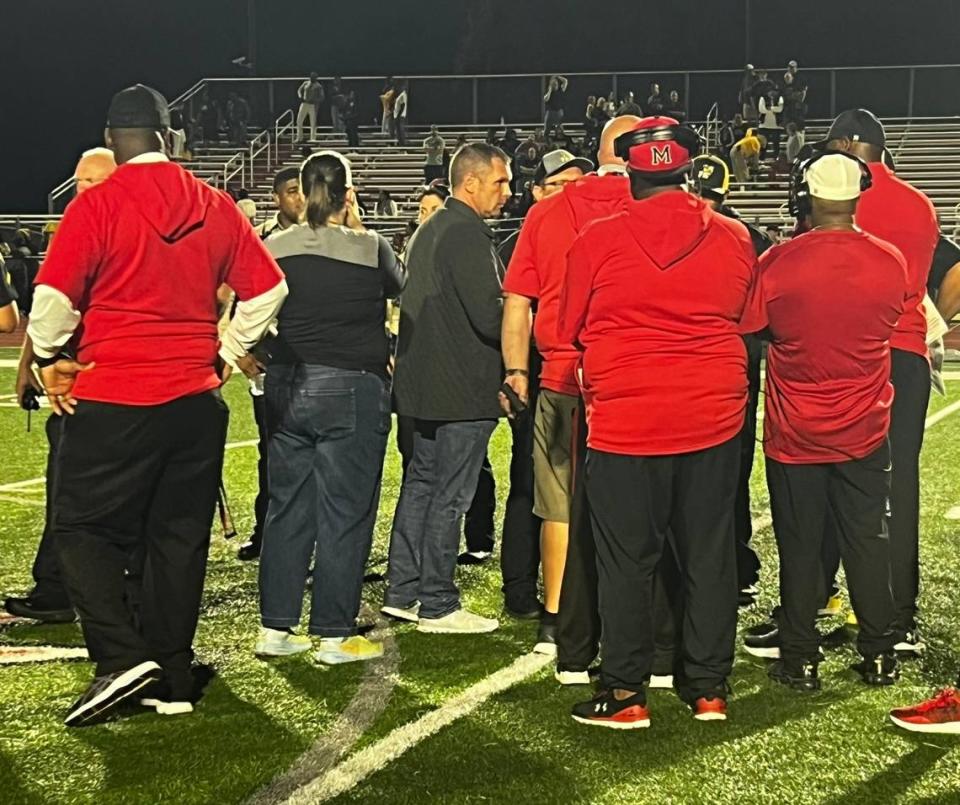 Coaches and school officials from Monroe and Forest Hills High Schools discuss what to do after a series of fights broke out during Friday’s game. The game was eventually called in the third quarter