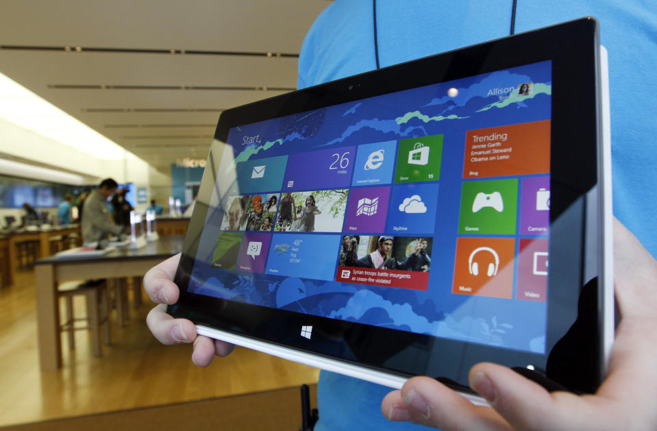 A Microsoft store product advisor displays the new Surface table computer as customers enter the store as it opens Friday, Oct. 26, 2012 in Seattle. Friday was the first day of sales for the new Windows 8 operating system and the company's new tablet computer, the Surface. (AP Photo/Elaine Thompson)