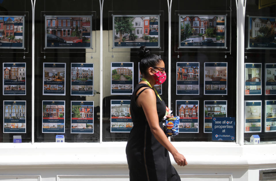 A woman wearing a protective face mask passes an estate agents window in north London. Chancellor Rishi Sunak has confirmed temporary plans to abolish stamp duty on properties up to 500,000 GBP in England and Northern Ireland as part of a package to dull the economic impact of the coronavirus. Picture date: Sunday July 12, 2020.